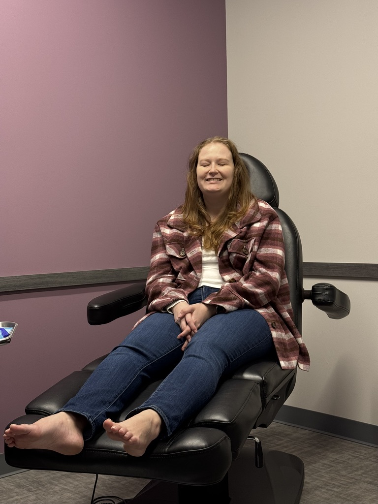 Leslie at a follow-up appointment, smiling in a plaid jacket