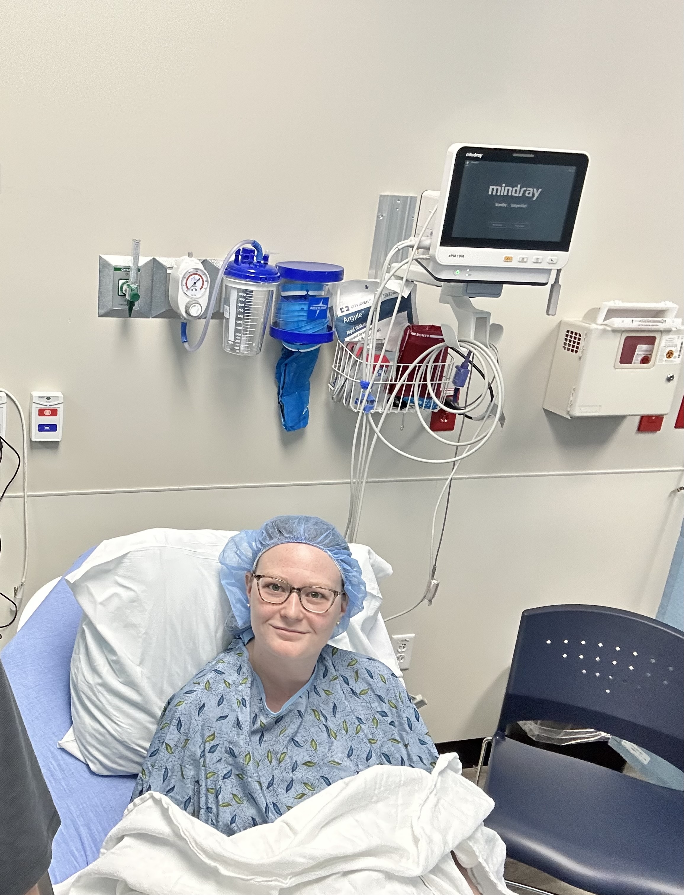 Leslie before a second procedure, smiling in a hospital gown